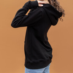 Black hoodie on woman. Long warm sleeve and patch pocket. Clothing for autumn or winter. Brown background. Square
