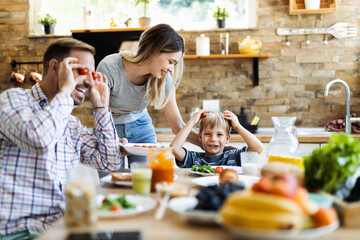 Happy mother serving food to her family while father and son having fun in dining room