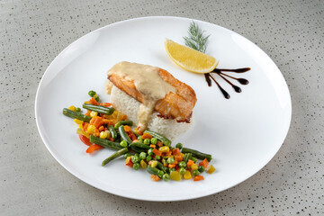 Bowl of rice with vegetables and salmon. Dish poured with sauce, macro photography.