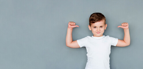 European guy is pro feeling proud and self-assured triumphing, being winner pointing at himself with thumbs tilting head looking confident and assertive in own skills, posing in white t-shirt