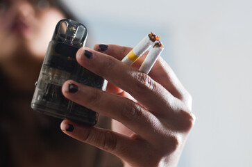 stop smoking start vaping concept. Cigarette vs e-cigarette concept. woman holding cigarette and...