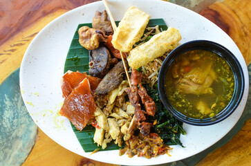 a photo of balinese rice dish of roast pork or usually called nasi campur babi guling with natural light.