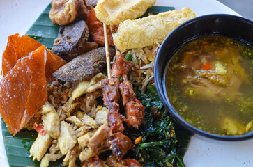 a photo of balinese rice dish of roast pork or usually called nasi campur babi guling with natural light.