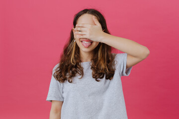 White preteen girl showing her tongue and covering her eyes