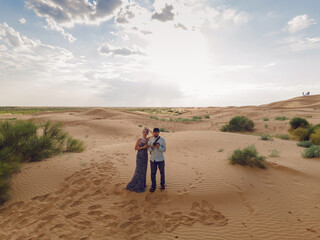 man and woman in a long dress launch a drone standing in the desert at sunset. go everywhere.