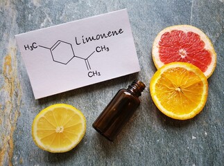 Structural chemical formula of limonene with fresh citrus fruit and a glass cosmetic bottle....