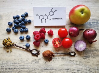 Structural chemical formula of quercetin molecule with fresh fruit and vegetable. Quercetin is a...