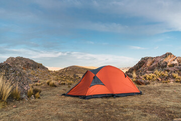 orange colored camp in the mountains in a sunset surrounded by rocks and yellow vegetation in the winter in the andes mountain range