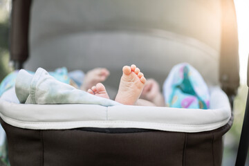 little cute feet of a newborn baby in a stroller, the baby sleeps in the stroller while walking,...