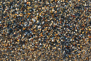 Fototapeta premium View of small colored pebbles on the seashore. Texture of small stones.