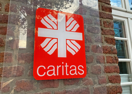 Heinsberg, Germany - July 23. 2022: Closeup of red sign with logo lettering of german welfare association Caritas on building wall