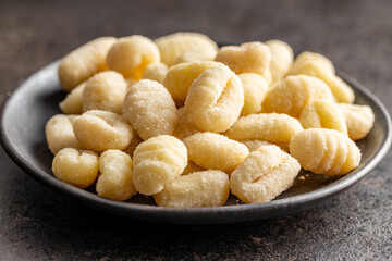 Uncooked potato gnocchi on plate. Tasty italian food.