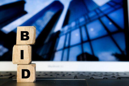 Bidding process. Auction paddles, flat hand holding plates. Finance or business, special offer. BID letter on wooden cube isolated over company building.