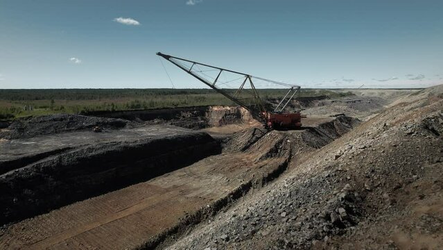 Huge dragliner excavator mining gold in an open pit. Aerial industrial quarry scene. Pollution, environment and ecology concept
