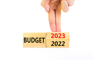 Planning 2023 budget new year symbol. Businessman turns a wooden cube and changes words Budget 2022 to Budget 2023. Beautiful white background, copy space. Business 2023 budget new year concept.