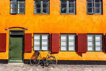 Fototapeta na wymiar Street with yellow Danish house and a bike in Copenhagen, Denmark, Europe