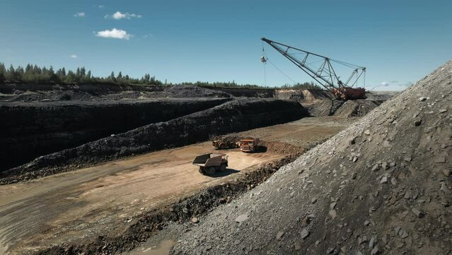 Huge dragliner excavator mining gold in an open pit. Dump truck and bullzdozer at work. Aerial industrial quarry scene. Pollution, environment and ecology concept