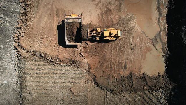 Dump truck and bullzdozer at work. Loading precious minerals in an open pit. Aerial industrial quarry scene. Pollution, environment and ecology concept