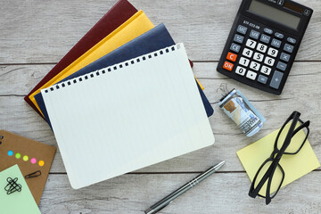blank spiral notepad and calculator on light wood background