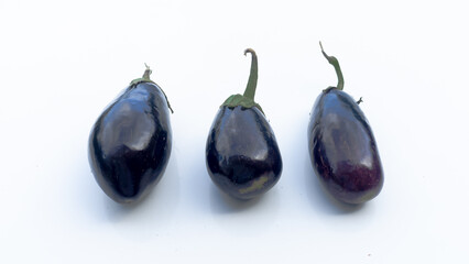 group of three organic eggplants from the garden on white surface