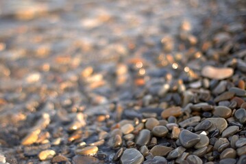 A sea wave rolls over a rocky beach, the concept of travel, calmness and reflection on a warm day, close-up, selective focus, bokeh.