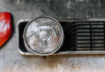 A round headlight from an old, antique car hangs on the wall in the museum close-up.