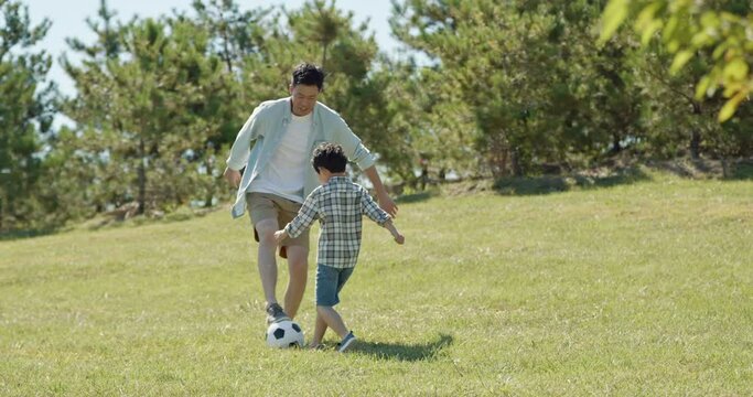 Happy father and son playing football in park,4K