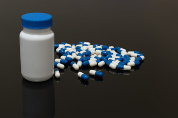 Medicine bottle and pills on black surface.  Selective focus.