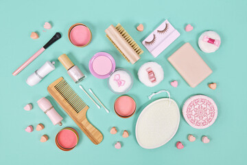 Pink makeup beauty products like brushes, powder or lipstick on teal blue background
