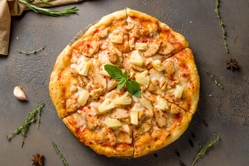 pizza Hawaiian with pineapple and chicken on brown concrete table top view