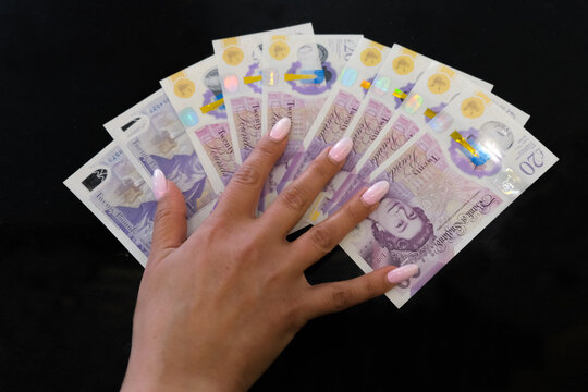 Pound, sterling notes in the hand of a girl on a black background.