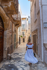 Fototapeta na wymiar Blonde girl walking near baroque building in Polignano a Mare, Bari, Puglia, Italy.