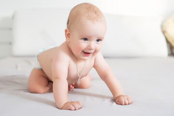 Adorable baby boy in white sunny bedroom. Newborn child relaxing in bed. Nursery for young children