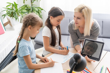 mother and two daughters doing homework writing and reading at home