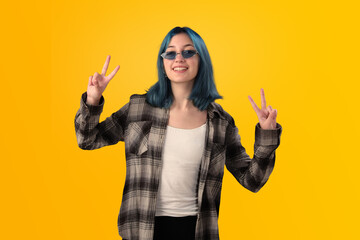 Smiling young woman student with blue hair doing positive gestures with her hands isolated over yellow background - 525699740