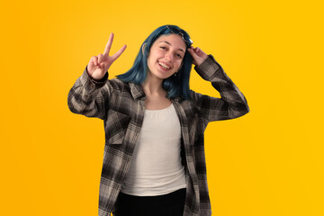 Smiling young woman student with blue hair doing positive gestures with her hands isolated over yellow background - 525699744
