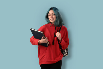 Cute young gilr student with blue hair books and a backpack over a cyan background - 525699952