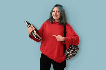 Cute young gilr student with blue hair books and a backpack over a cyan background - 525699968