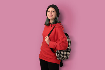 Cute young gilr student with blue hair and a backpack isolated over pink background - 525699974