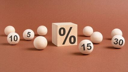 percent sign on wooden cubes against broun background with wooden balls. concept of sale and discount