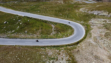 Luftaufnahme mit einer Drohne von einer engen Kurve mit Motorradfahrer im Gebirge