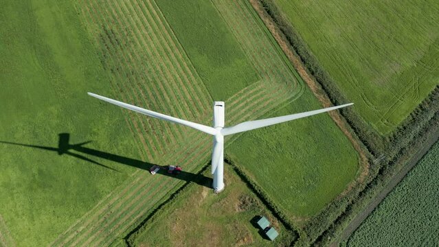 Aerial high level top down birds eye view clip of a wind turbine in a small rural wind farm in the English countryside