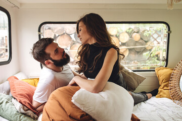 Young beautiful loving couple travelling across country in the van. Millennial man and woman in a travel camper. Cozy atmosphere, vacations vibe