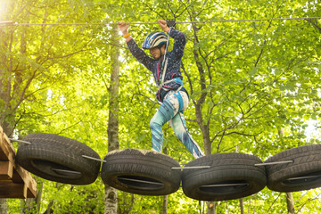 adventure climbing high wire park - children on course rope park. Portrait of cute little girl walk on a rope bridge in rope park
