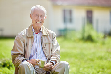 White teeth person, toothy smile of an elderly man 75 years old who sits outside in front of his house.