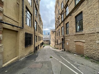 View down, Greenaire Place, with former Victorian warehouses, a derelict mill, and university buildings in the distance in, Bradford, UK