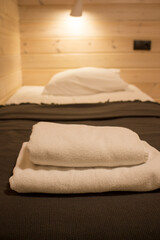 Fototapeta na wymiar Prepared fresh bed in a wooden house, scene in hotel room.