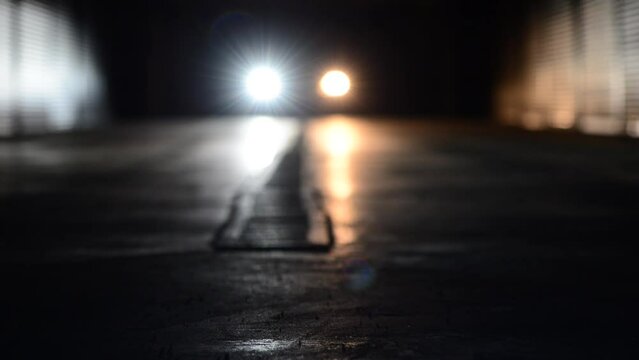 comparative characteristics of two types of headlight bulbs - led bulb vs halogen bulb simultaneously installed on the low beam of car headlights with moving car inside dark garage 