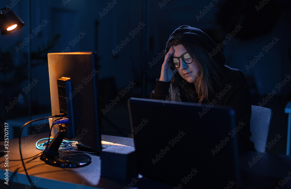 Poster cybercrime, hacking and technology concept - female hacker in dark room writing code or using comput