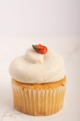 Close up of a vanilla cupcake with buttercream frosting and flower - obrazy, fototapety, plakaty